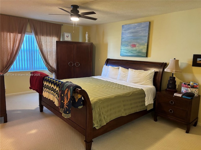 bedroom with ceiling fan, light carpet, and a textured ceiling