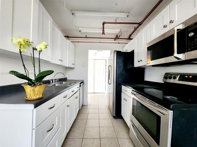 kitchen with sink, light tile patterned floors, stainless steel appliances, and white cabinets