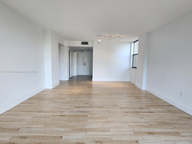 spare room with rail lighting and light wood-type flooring