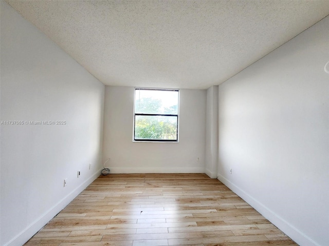 empty room with light hardwood / wood-style floors and a textured ceiling