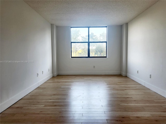 spare room featuring a textured ceiling and light wood-type flooring