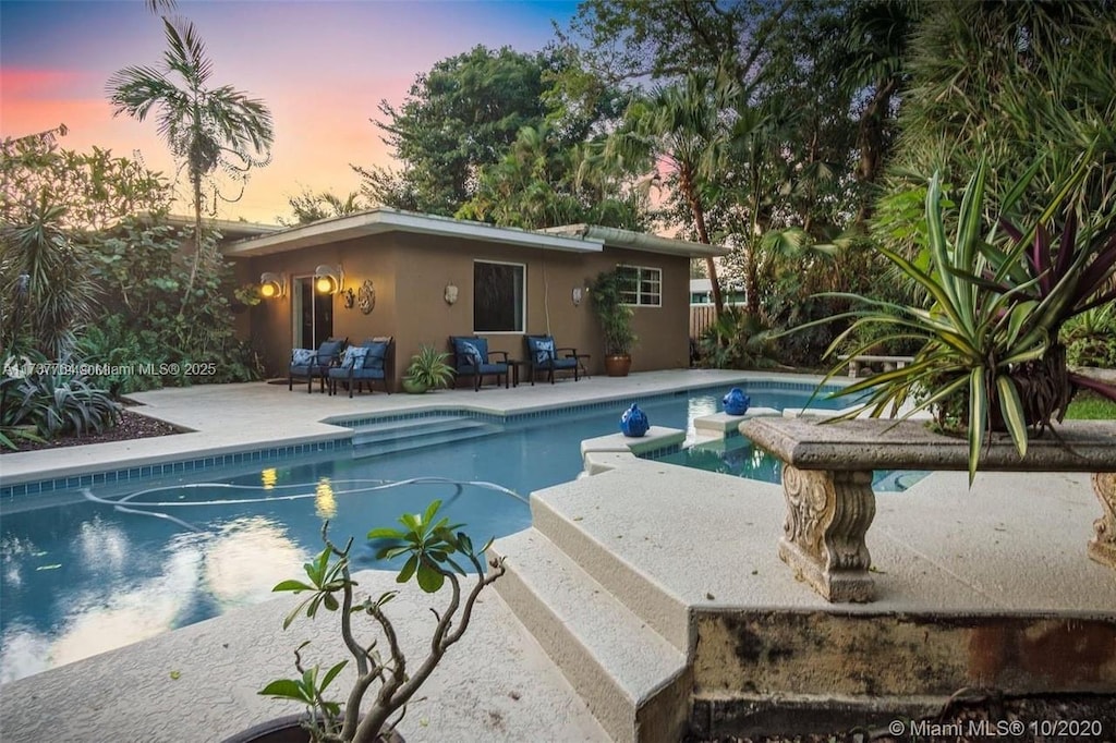 pool at dusk with a patio area