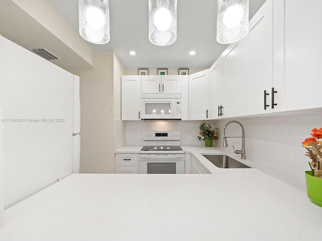 kitchen with light countertops, visible vents, white cabinets, a sink, and white appliances