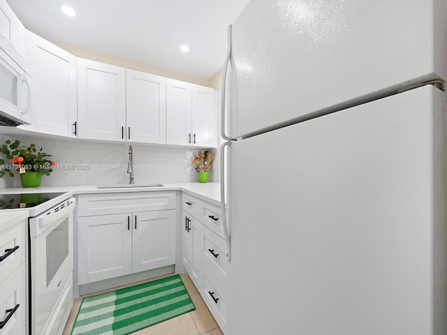 kitchen with white appliances, white cabinets, a sink, and light countertops