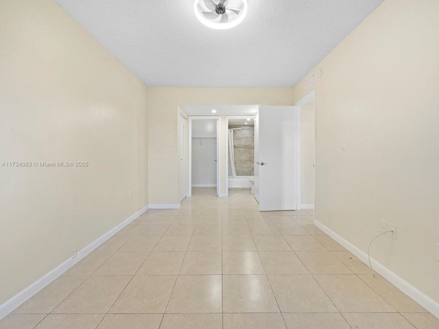 unfurnished room featuring light tile patterned floors, a textured ceiling, and baseboards