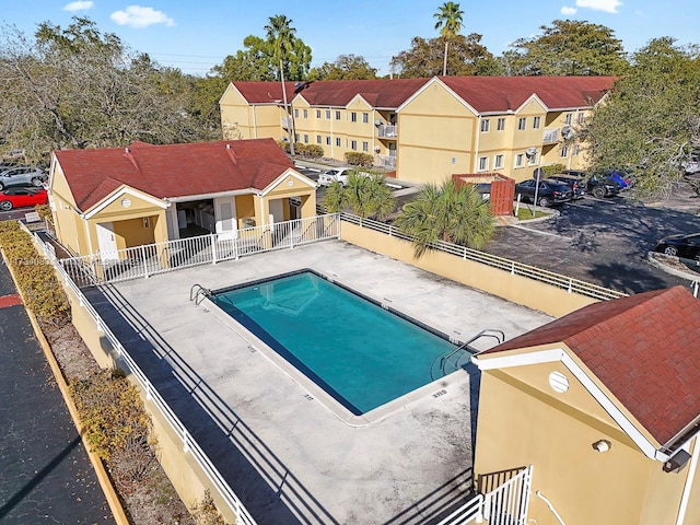 community pool featuring a residential view, a patio area, and fence