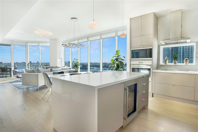 kitchen featuring tasteful backsplash, beverage cooler, a wall of windows, black appliances, and light hardwood / wood-style flooring