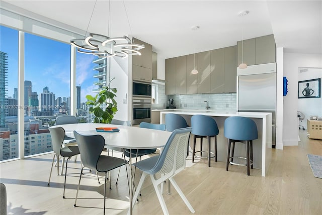 dining room featuring expansive windows, a notable chandelier, sink, and light wood-type flooring