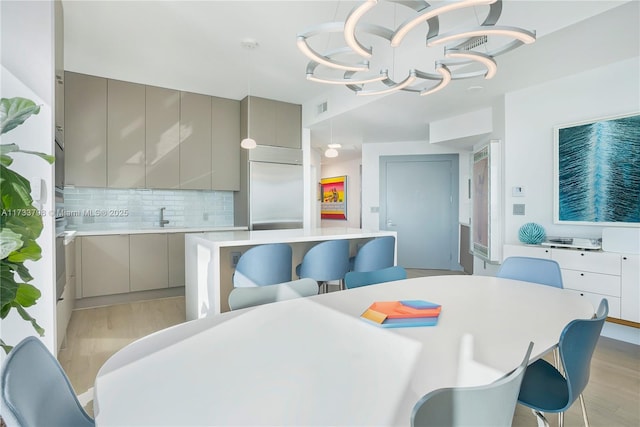 dining space featuring sink, a notable chandelier, and light hardwood / wood-style floors