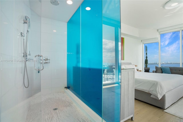 bathroom with a shower with shower door, wood-type flooring, and a water view