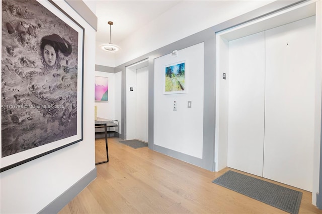 hall featuring elevator and light hardwood / wood-style flooring