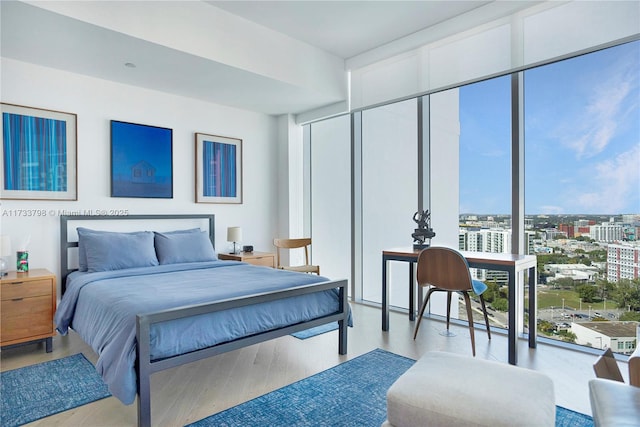 bedroom featuring a wall of windows and light hardwood / wood-style flooring