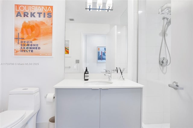 bathroom featuring vanity, toilet, and tiled shower