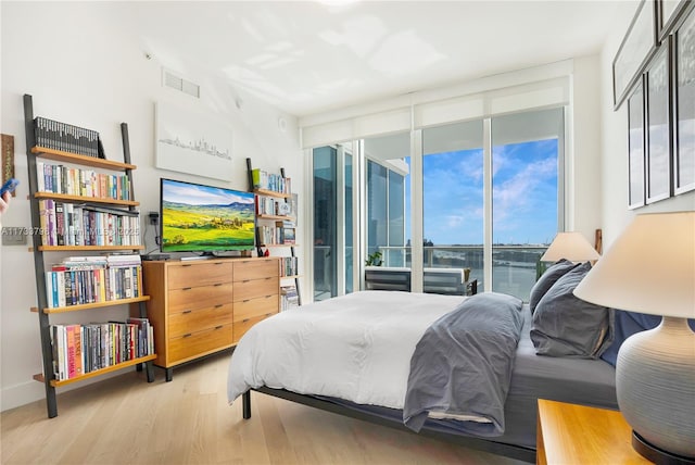 bedroom featuring floor to ceiling windows, access to exterior, and light hardwood / wood-style floors