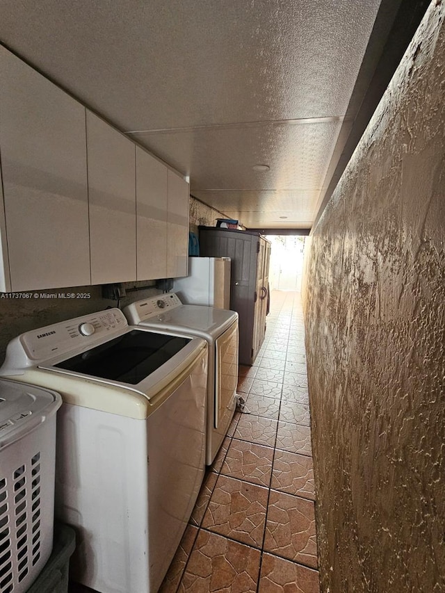 laundry room with cabinets, independent washer and dryer, and a textured ceiling