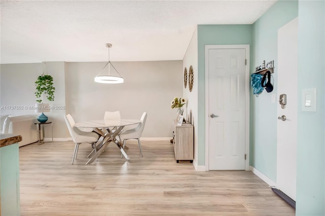 dining area with light wood-type flooring and baseboards