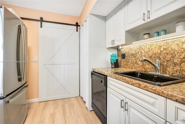 kitchen featuring sink, stainless steel fridge, dishwasher, white cabinets, and a barn door