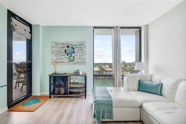 interior space with expansive windows, a water view, hardwood / wood-style floors, and a textured ceiling