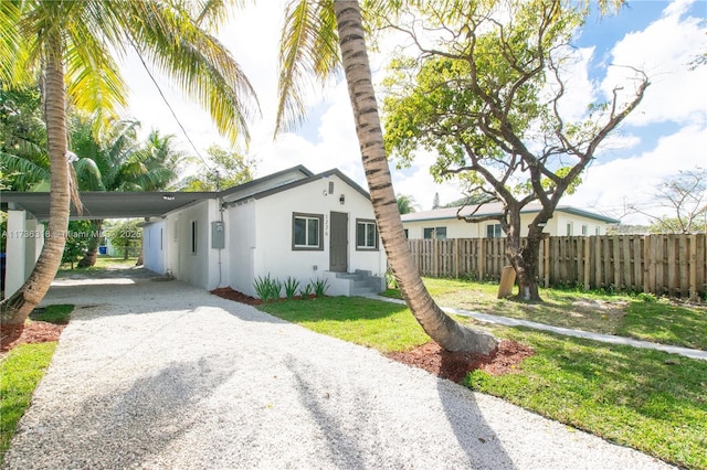 exterior space featuring stucco siding, fence, a yard, gravel driveway, and a carport