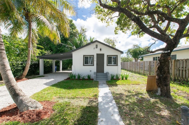 bungalow-style home featuring stucco siding, a carport, gravel driveway, and fence