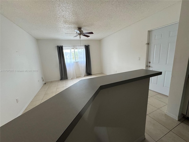 spare room with light tile patterned floors, a textured ceiling, and ceiling fan