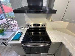 kitchen with stainless steel electric stove and wall chimney exhaust hood