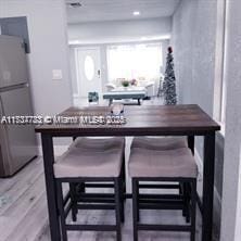 bar with wood-type flooring and fridge