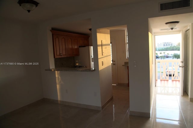 kitchen with tile patterned floors, white refrigerator with ice dispenser, and decorative backsplash