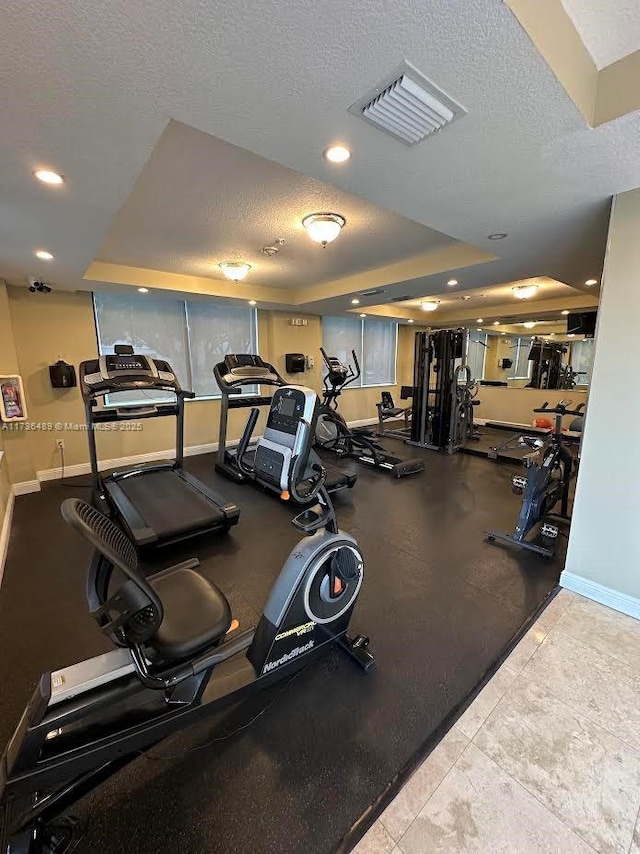 exercise room with a textured ceiling and a tray ceiling