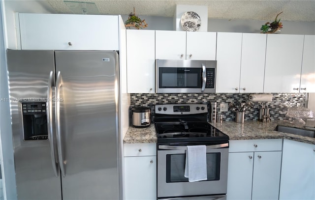 kitchen featuring backsplash, appliances with stainless steel finishes, dark stone counters, and white cabinets