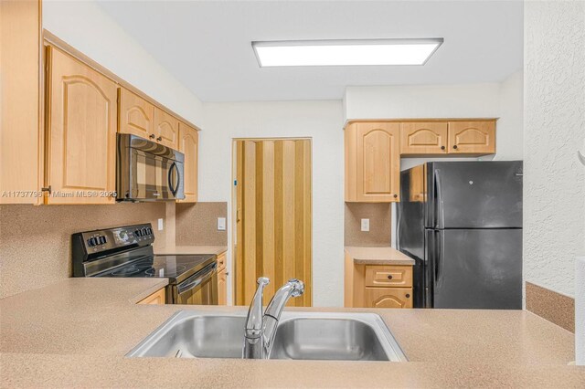 kitchen featuring light brown cabinetry, sink, and black appliances