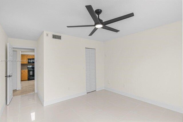 tiled empty room featuring ceiling fan