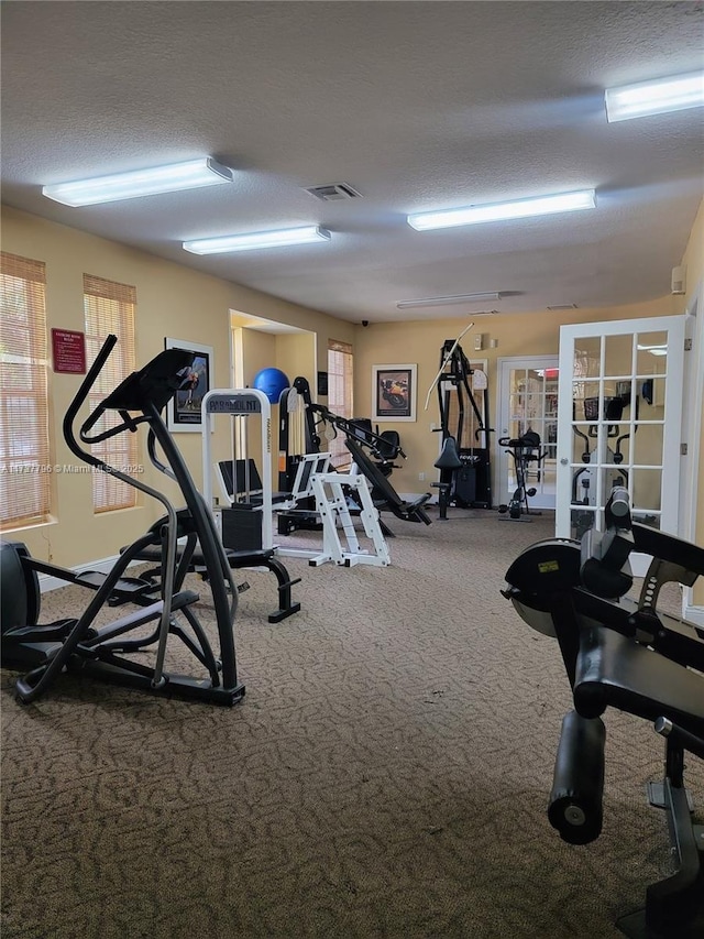 exercise room featuring french doors, a textured ceiling, and carpet