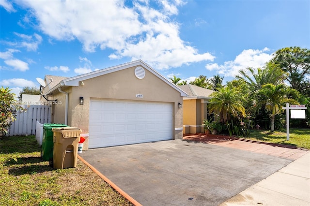 single story home featuring driveway, a garage, fence, and stucco siding