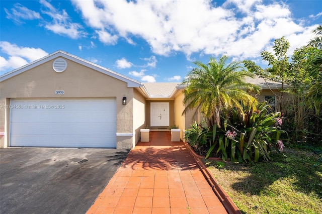 single story home with an attached garage, driveway, and stucco siding