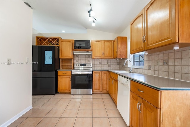 kitchen with lofted ceiling, light countertops, a sink, under cabinet range hood, and black appliances