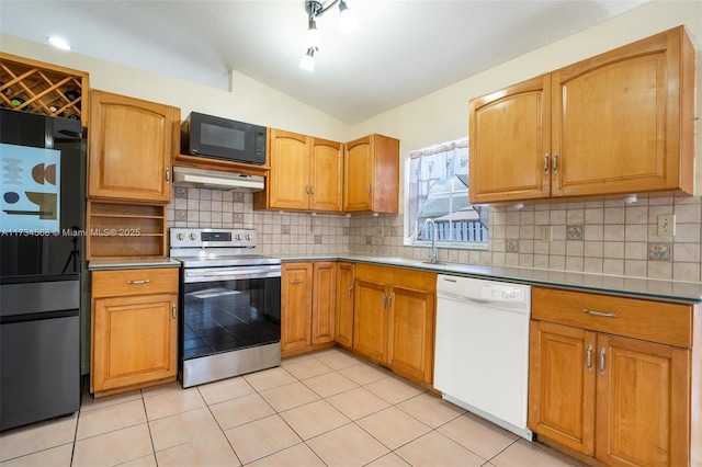 kitchen featuring light tile patterned flooring, vaulted ceiling, a sink, under cabinet range hood, and black appliances