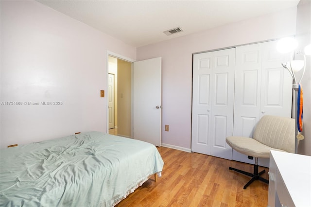 bedroom featuring light wood-type flooring, a closet, and visible vents