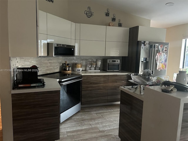 kitchen with electric stove, backsplash, and white cabinets