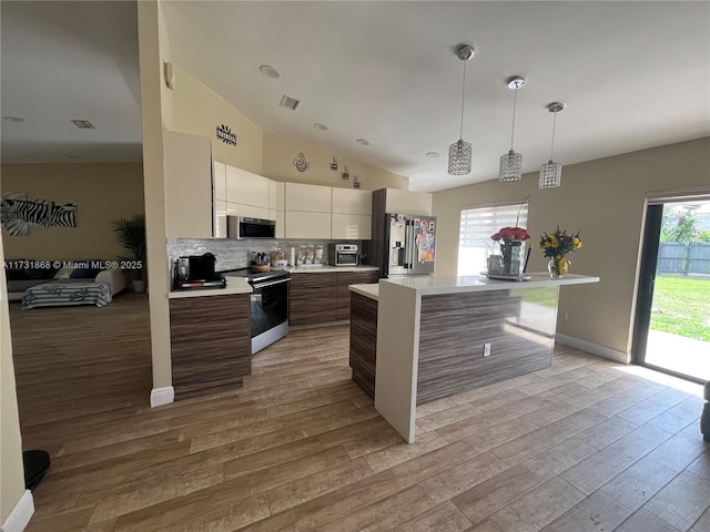 kitchen with appliances with stainless steel finishes, a kitchen island, light hardwood / wood-style floors, and decorative light fixtures