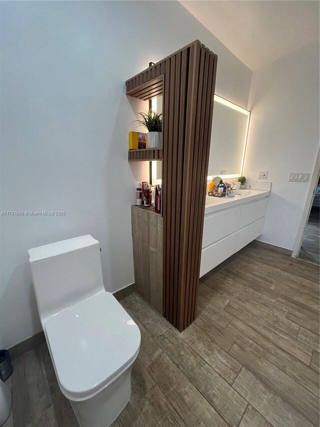 bathroom featuring toilet, vanity, and hardwood / wood-style floors