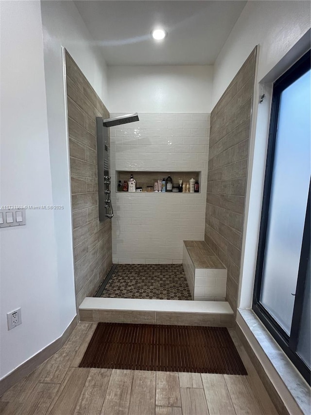 bathroom with hardwood / wood-style floors and a tile shower