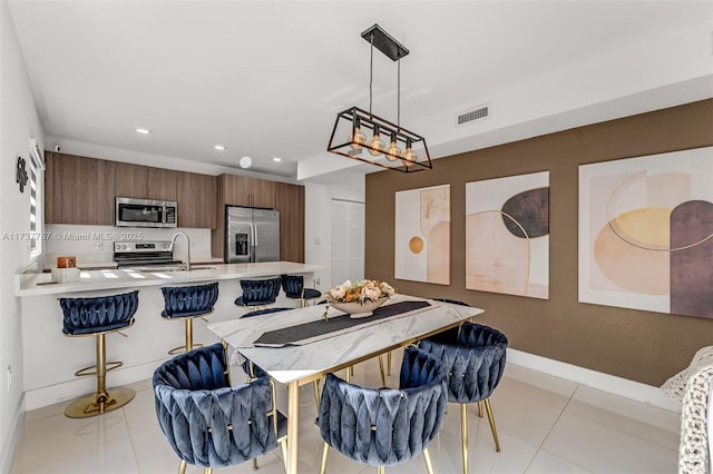 kitchen with a breakfast bar, stainless steel appliances, light tile patterned flooring, decorative light fixtures, and kitchen peninsula