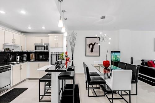 kitchen featuring white cabinetry, appliances with stainless steel finishes, decorative light fixtures, and a breakfast bar area