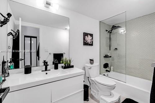 full bathroom featuring tiled shower / bath, vanity, and toilet