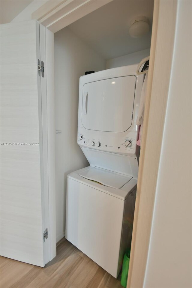 washroom with stacked washer and dryer and light wood-type flooring