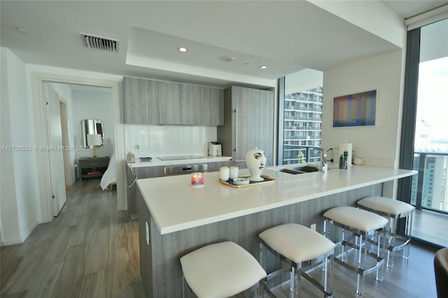 kitchen with a breakfast bar, hardwood / wood-style floors, sink, stainless steel oven, and kitchen peninsula