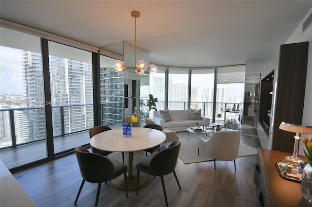 dining room featuring an inviting chandelier, dark wood-type flooring, and a wall of windows