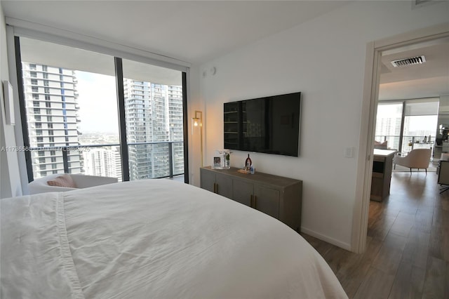 bedroom with a wall of windows and dark hardwood / wood-style floors