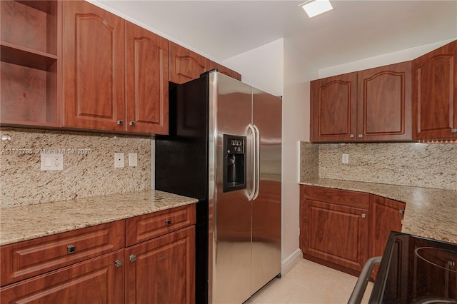 kitchen with light tile patterned flooring, light stone counters, stainless steel fridge, range with electric cooktop, and decorative backsplash